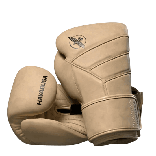 De linker Hayabusa T3 LX bokshandschoen in tan, liggend op de rechter met focus op het valklogo en de gestikte details van de constructie.