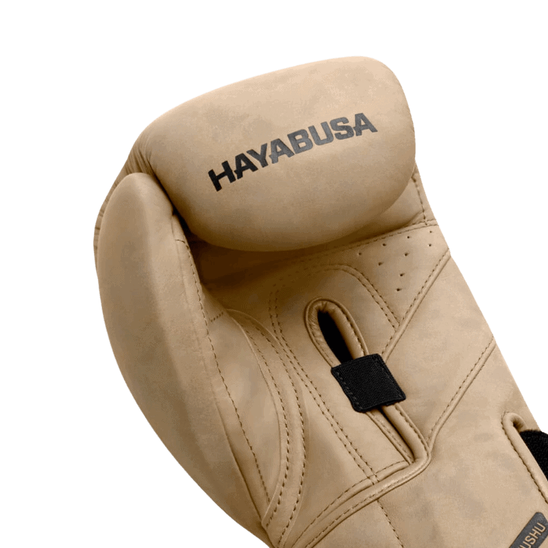 Close-up van de bovenkant van een Hayabusa T3 LX bokshandschoen in tan met het zwarte Hayabusa-logo en een ventilatiegat.