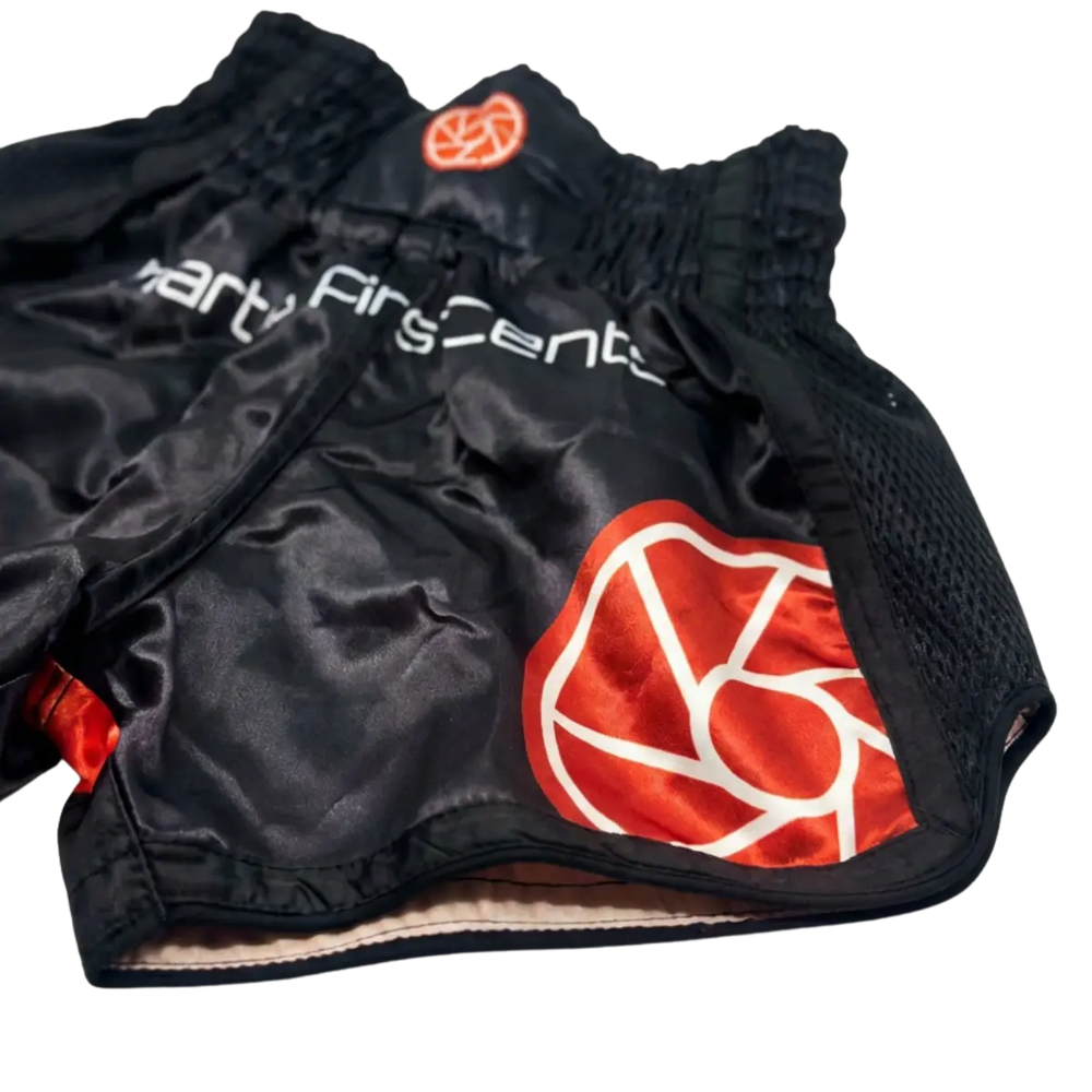 Zwart kickboks broekje close-up met rood logo en glanzende stofdetails