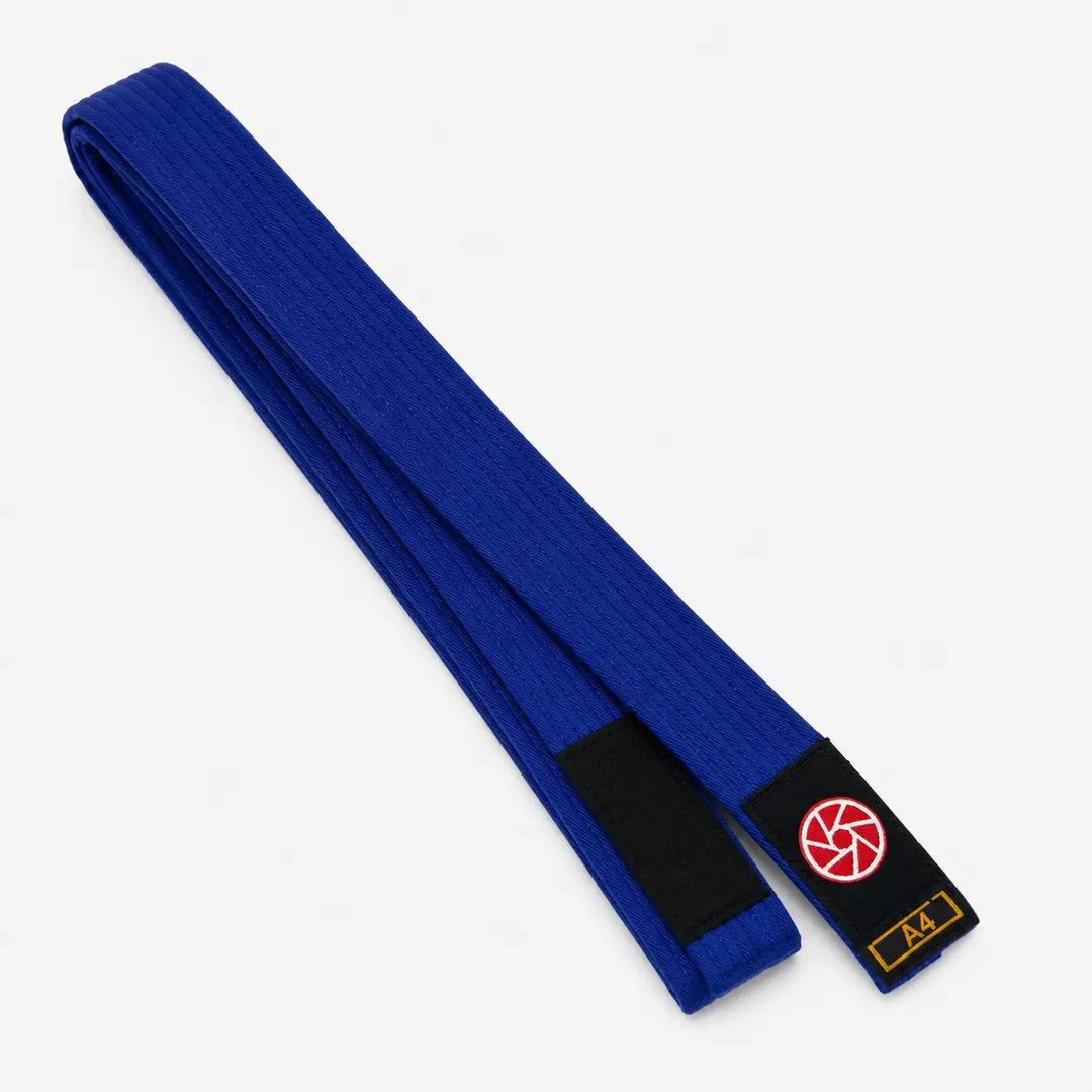 Blauwe BJJ band in maat A4 met zwarte uiteinden en een rood-wit logo op het label. De geweven structuur en lange pasvorm maken de band geschikt voor BJJ-trainingen, graduaties en dagelijks gebruik op de mat.