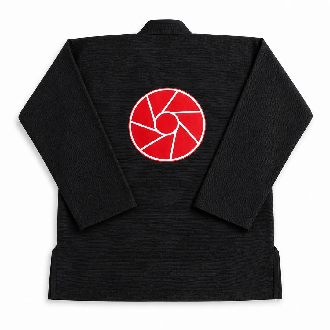 Zwarte BJJ gi gefotografeerd vanaf de achterkant met een opvallend rood logo op de rug. De stevige stof en klassieke pasvorm maken de gi geschikt voor intensieve BJJ-trainingen en grapplinglessen.