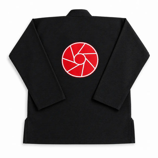 Zwarte BJJ gi gefotografeerd vanaf de achterkant met een opvallend rood logo op de rug. De stevige stof en klassieke pasvorm maken de gi geschikt voor intensieve BJJ-trainingen en grapplinglessen.