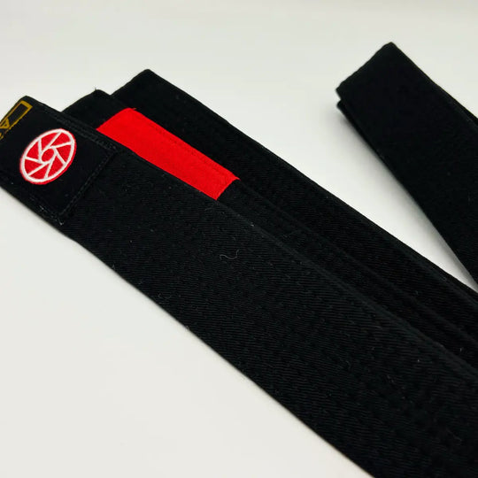 Zwarte Martial Arts Center band met rood gradenstuk en rond rood logo op wit studioachtergrond.