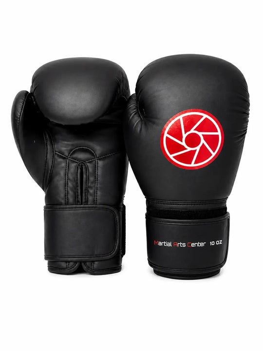 Zwarte bokshandschoenen van 10 oz met rood-wit logo op de bovenkant en Martial Arts Center branding op de polsband. De stevige padding, duimbescherming en brede klittenbandsluiting maken de handschoenen geschikt voor boksen, kickboksen en intensieve stoottrainingen.