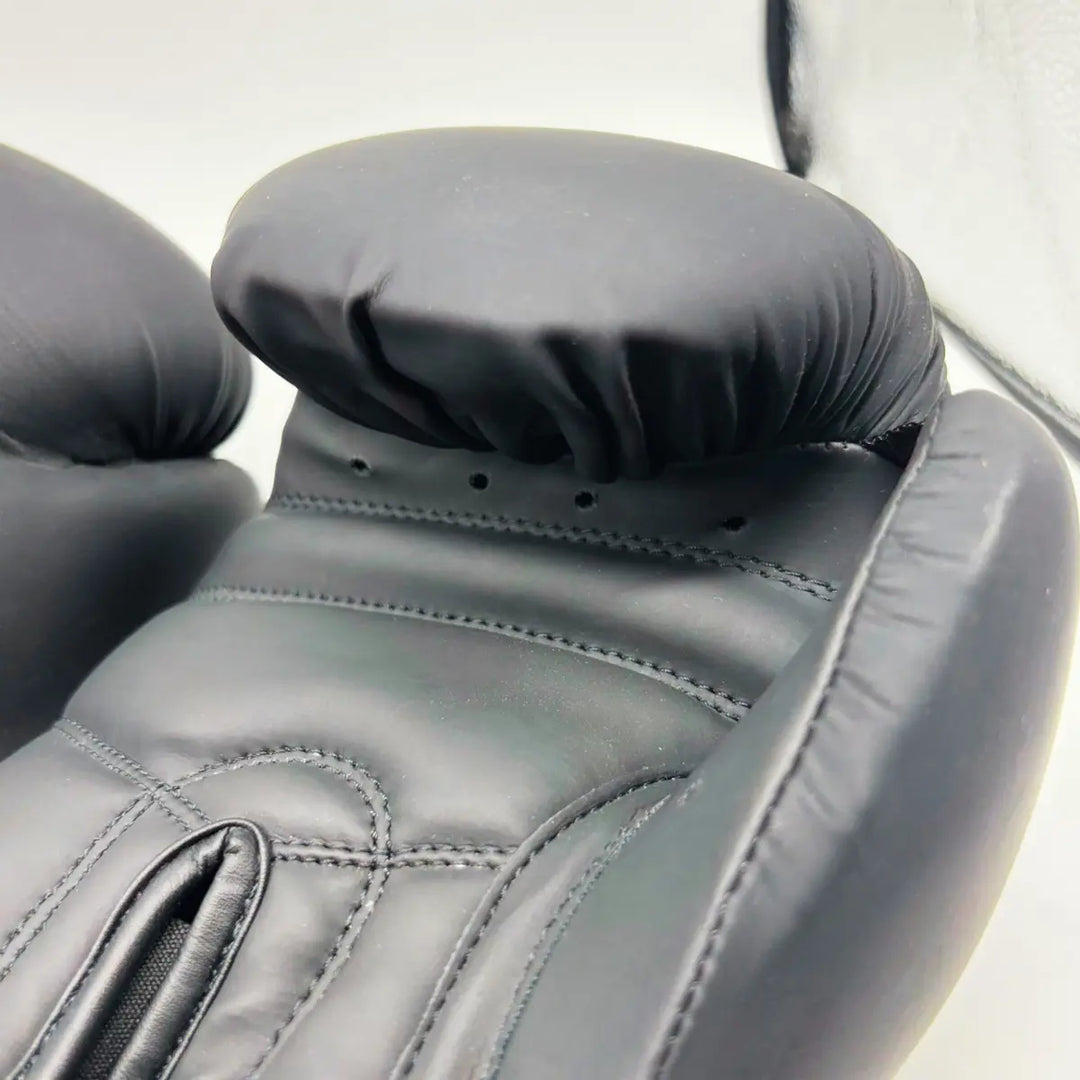 Close-up van zwarte Martial Arts Center bokshandschoen met dikke palm- en duimpadding en zichtbare stiksels.