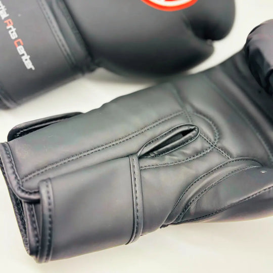 Close-up van zwarte Martial Arts Center bokshandschoen met lange klittenbandsluiting en zichtbare stiknaden aan de palmzijde.