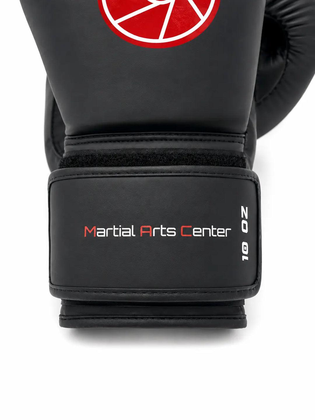 Close-up van een zwarte bokshandschoen met Martial Arts Center logo op de polsband en maat 10 oz. De brede klittenbandsluiting en stevige padding bieden ondersteuning en bescherming tijdens boksen, kickboksen en intensieve stoottrainingen.