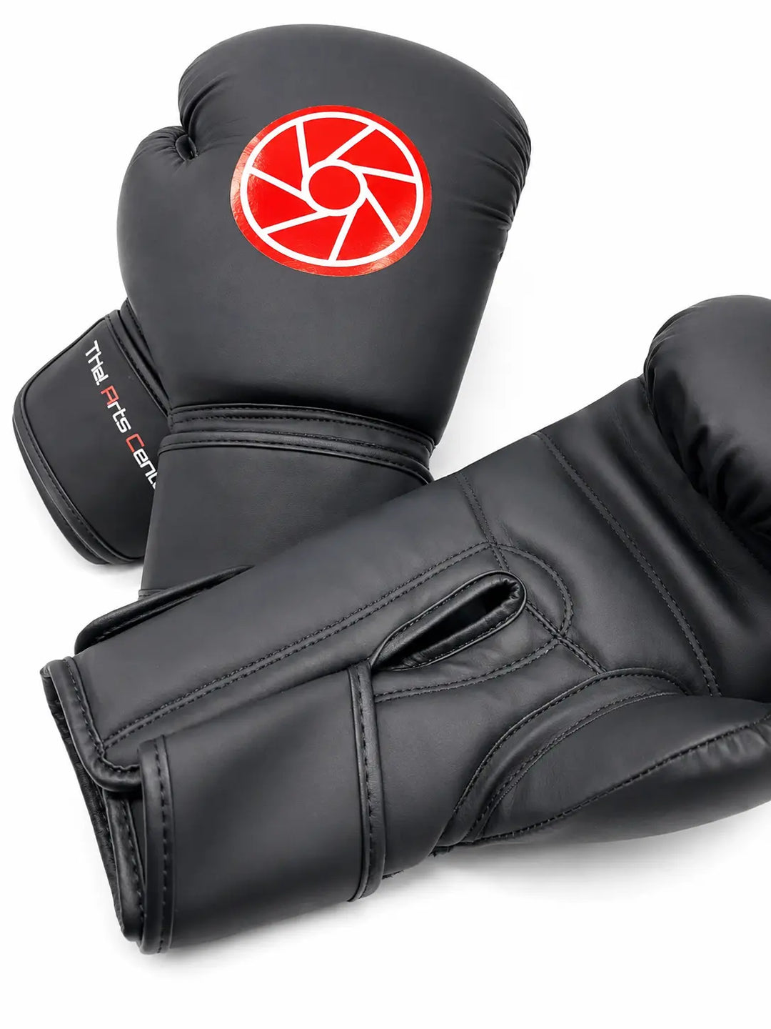 Zwarte bokshandschoenen met rood-wit logo op de bovenkant en Martial Arts Center branding op de polsband. De stevige padding, duimbescherming en brede klittenbandsluiting maken de handschoenen geschikt voor boksen, kickboksen en intensieve stoottrainingen.
