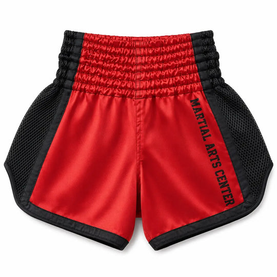 Rood kickboksbroekje met zwarte meshpanelen, brede elastische tailleband en Martial Arts Center op de zijkant. De glanzende stof en ruime pasvorm maken het broekje geschikt voor kickboksen, Muay Thai en intensieve trainingen.