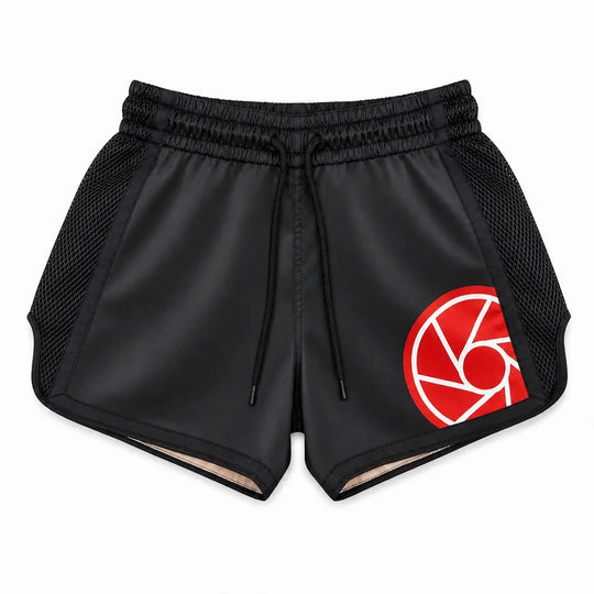 Zwart kickboksbroekje met brede elastische tailleband, verstelbaar koord en zwarte meshpanelen aan de zijkanten. Het rood-witte logo en de ruime pasvorm maken het broekje geschikt voor kickboksen, Muay Thai en intensieve trainingen.