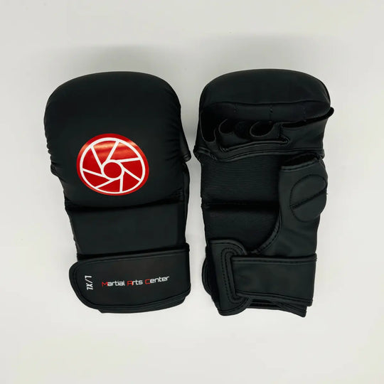 Bovenaanzicht van een paar zwarte Martial Arts Center MMA-handschoenen met rood rond logo en openvingerdesign op witte achtergrond.