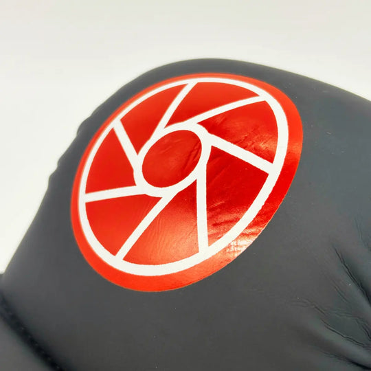Close-up van zwarte Martial Arts Center trainingshandschoen met rond rood logo op de knokkels.
