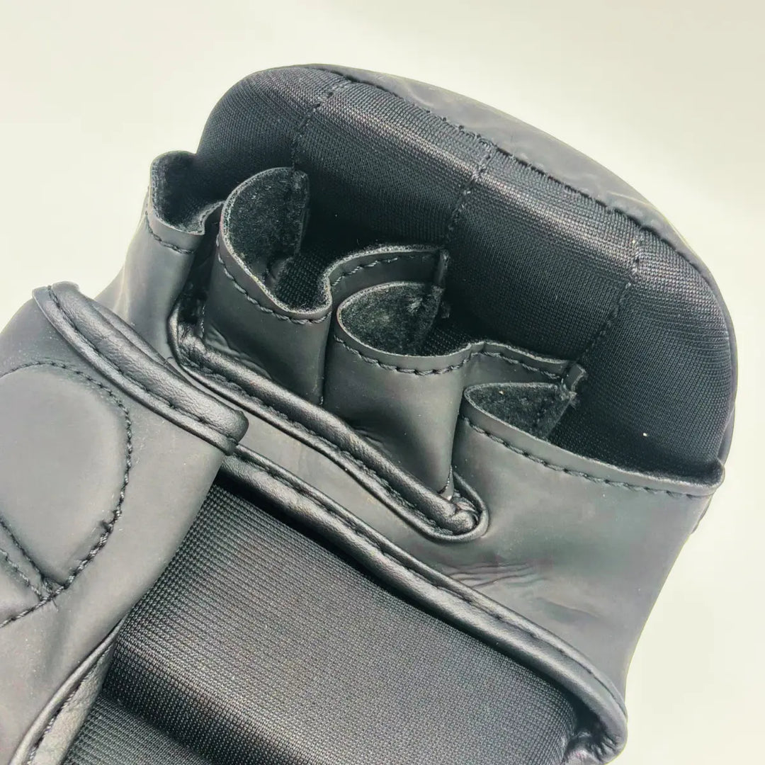Close-up van zwarte Martial Arts Center MMA-handschoen met openvingerdesign en dikke knokkelpadding.