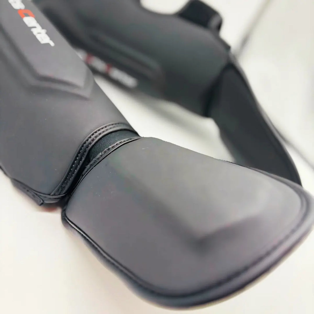 Close-up van zwarte Martial Arts Center scheenbeschermer met extra wreefbeschermer en verstevigde stiknaden.