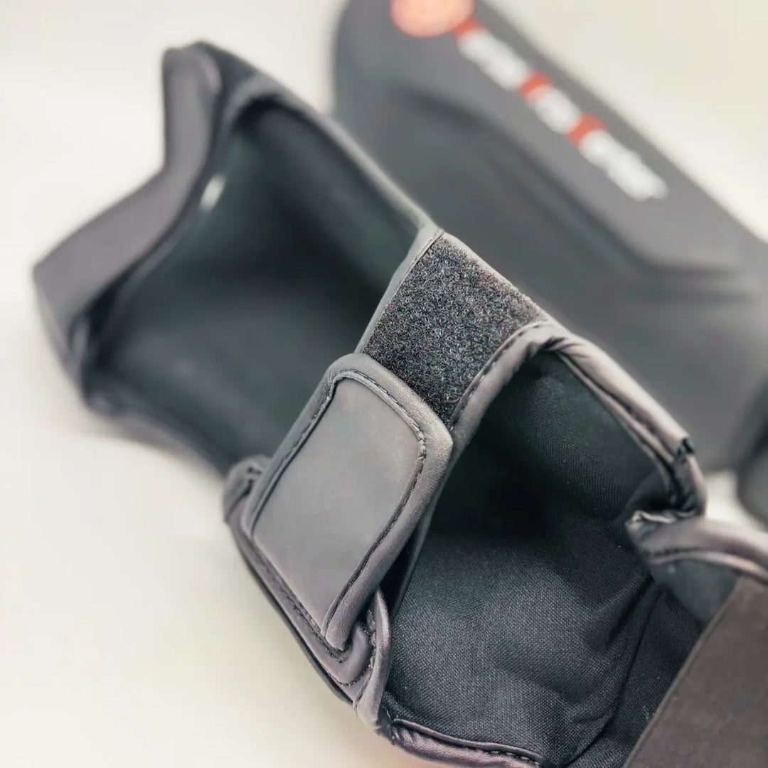 Close-up van zwarte Martial Arts Center scheenbeschermer met verstelbare klittenbandsluiting aan de achterkant.