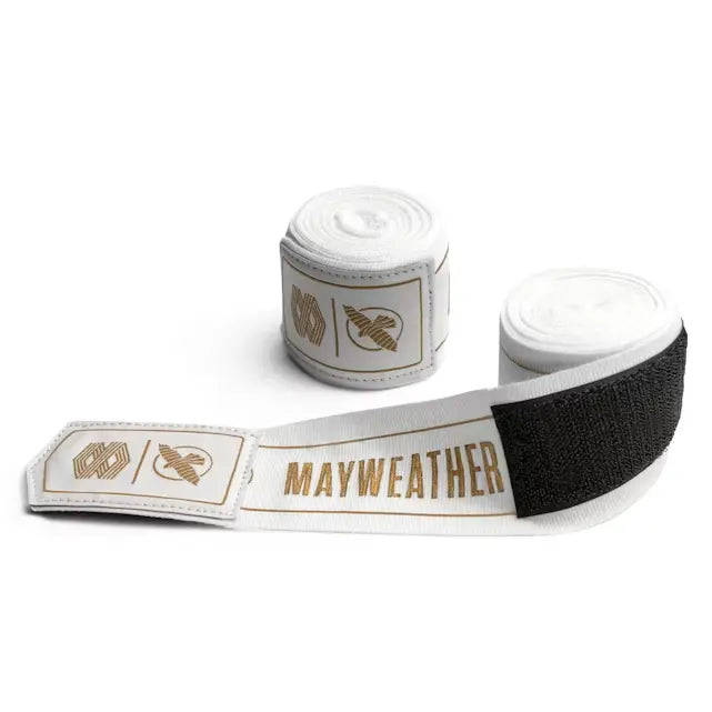 Witte Mayweather Hayabusa handwraps opgerold met gouden opdruk en klittenband sluiting, geschikt voor bescherming tijdens boksen en vechtsporttraining