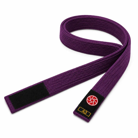 Paarse BJJ band in maat A3 met zwarte uiteinden en een rood-wit logo op het label. De stevige geweven structuur maakt de band geschikt voor BJJ-trainingen, graduaties en dagelijks gebruik op de mat.