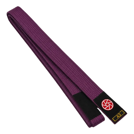 Paarse BJJ band in maat A3 met zwarte uiteinden en een rood-wit logo op het label. De stevige geweven structuur en lange pasvorm maken de band geschikt voor BJJ-trainingen, graduaties en dagelijks gebruik op de mat.