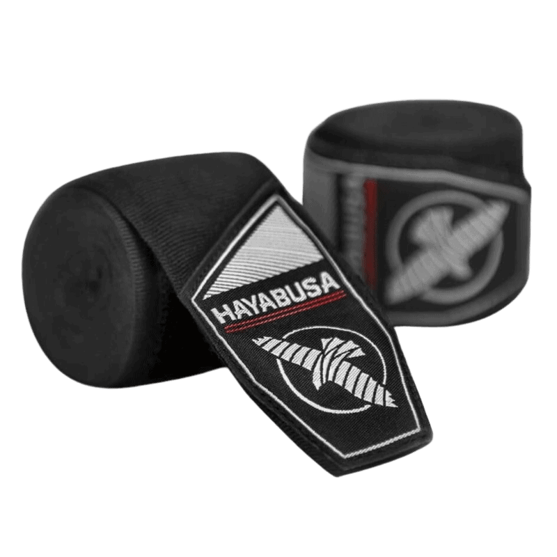 Een opgerolde rood-zwarte bandage met een geweven 'Hayabusa' logo op een zwart etiket, naast een zwarte bandagehouder met het witte Hayabusa logo.