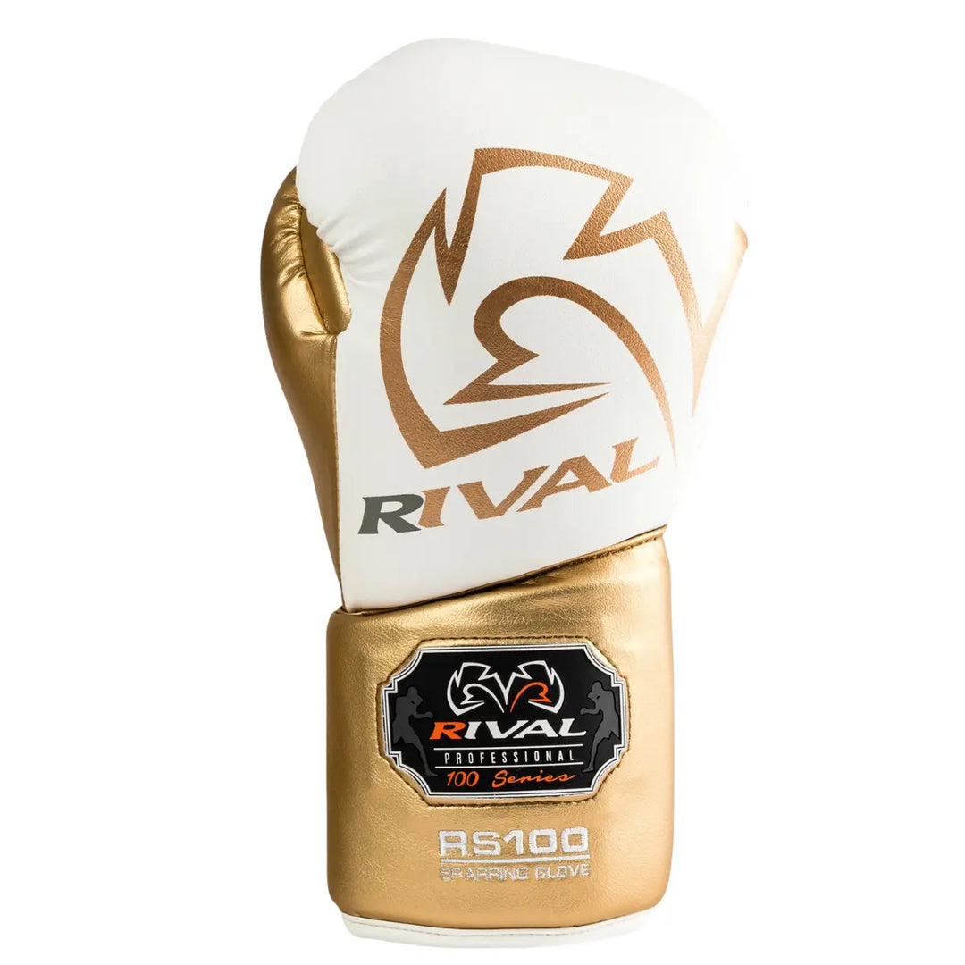 De Rival Bokshandschoen RS100 Professional Wit Goud is afgebeeld op een witte achtergrond en toont een elegante combinatie van wit en metallic goud. Het grote Rival-logo siert de bovenkant, terwijl het RS100 Professional-embleem de exclusieve 100 Series benadrukt. Deze foto straalt luxe, vakmanschap en professionele kwaliteit uit, ideaal voor vechters met oog voor detail.