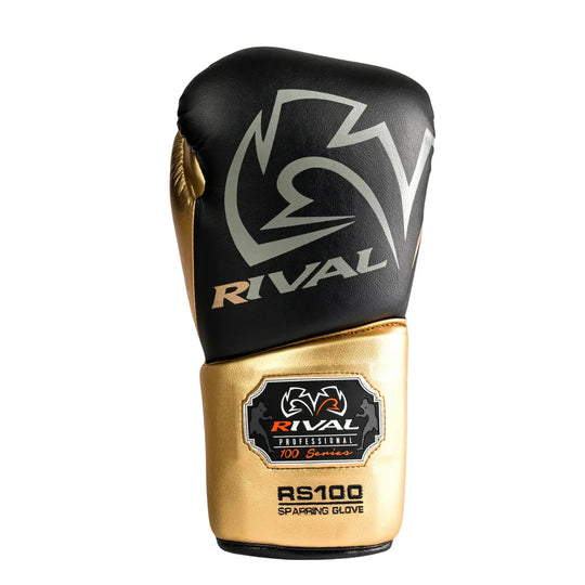 De Rival Bokshandschoen RS100 Professional Zwart Goud is afgebeeld op een witte achtergrond met een elegante combinatie van matzwart en metallic goud. Het grote Rival-logo siert de bovenkant van de handschoen, terwijl het RS100-embleem op de manchet de professionele kwaliteit benadrukt. De foto straalt luxe, kracht en precisie uit, perfect voor boksers die topprestaties eisen.