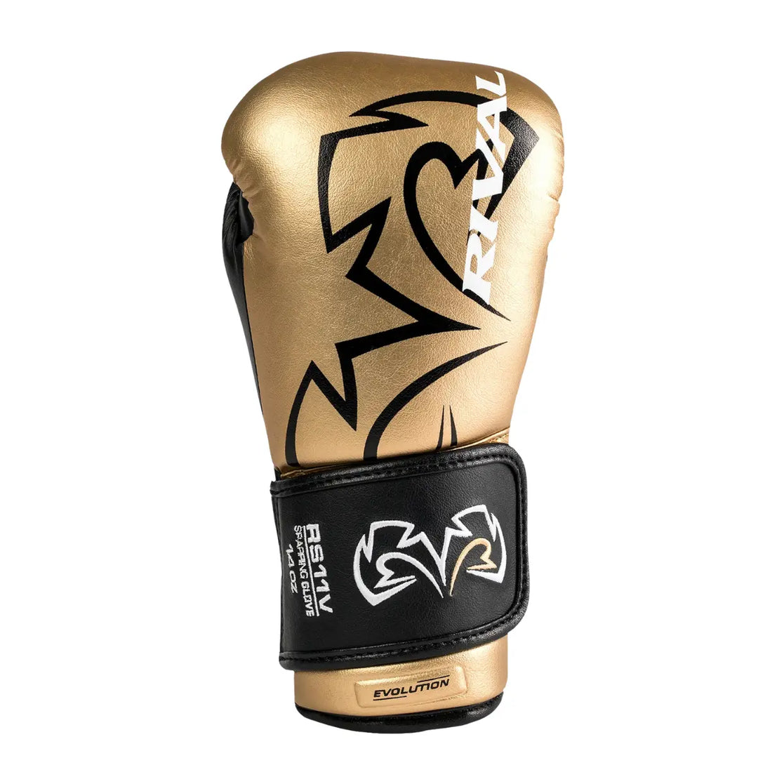 De Rival Bokshandschoen RS11V Evolution Goud staat rechtop met het zwarte Rival-logo prominent zichtbaar op de gouden buitenzijde. De polsband in zwart met goudaccenten toont het “Evolution”-label en zorgt voor een stevige sluiting. De afbeelding benadrukt het elegante ontwerp, de glanzende afwerking en de professionele kwaliteit van deze premium sparringhandschoen.