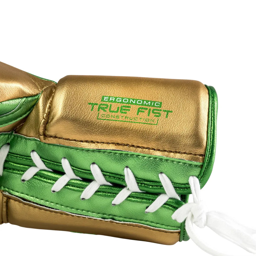De Rival Bokshandschoen RS100 Detail Groen Goud toont een close-up van de veterzijde van de handschoen met het opschrift “Ergonomic True Fist Construction”. De metallic gouden en groene afwerking benadrukt de luxe uitstraling, terwijl de witte veter en strakke stiksels de precisie van het vakmanschap laten zien. Deze foto legt de hoogwaardige constructie en ergonomische pasvorm van de handschoen perfect vast.