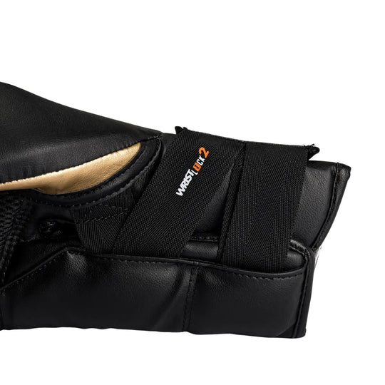 Close-up van de Rival Bokshandschoenen RS11V Evolution Goud, met focus op de polssluiting en het “Wrist Lock 2”-systeem. De afbeelding toont het zwarte en gouden leer, de dubbele klittenbandbanden en de precieze afwerking die zorgt voor extra polsstabiliteit en ondersteuning tijdens intensieve bokstrainingen.