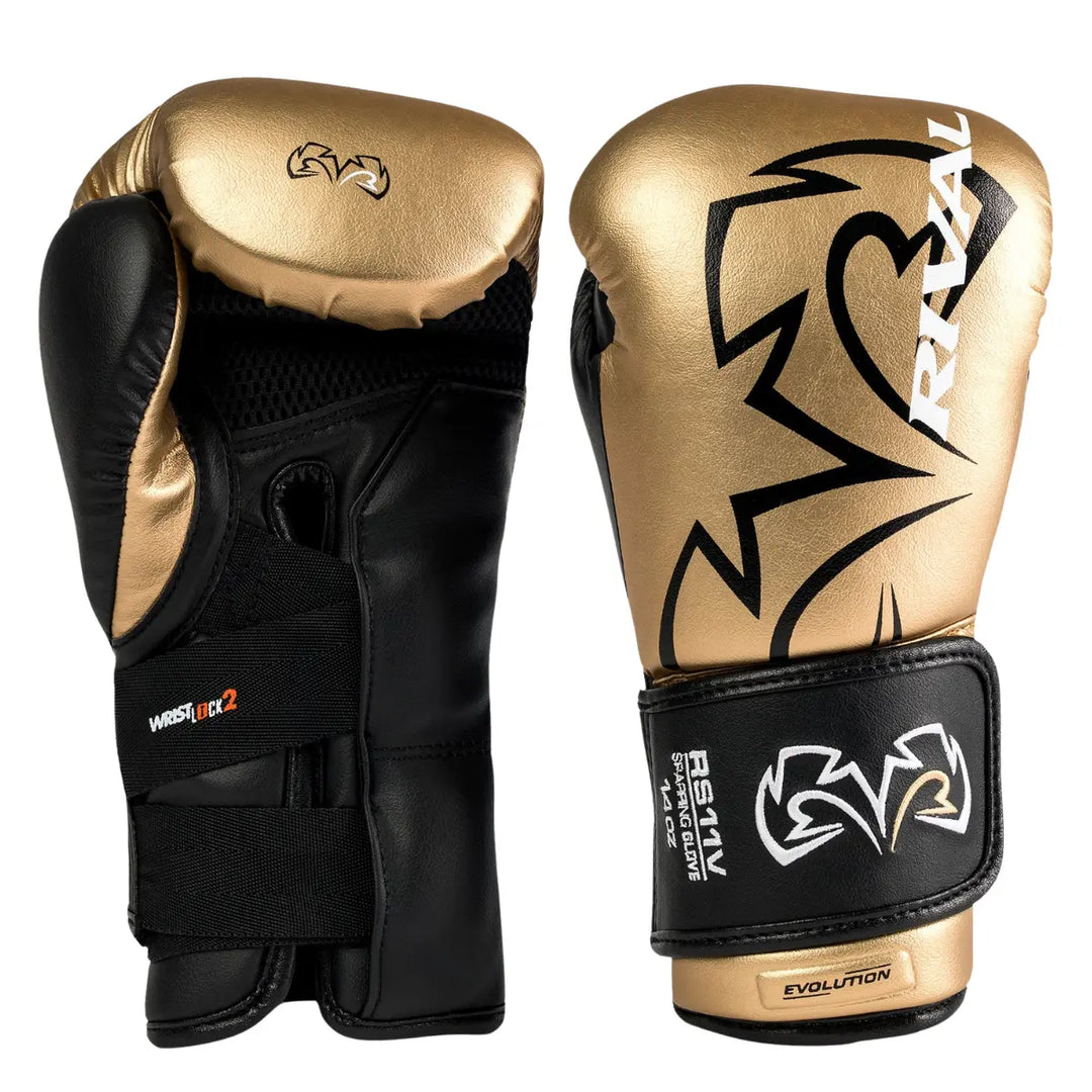 Een paar Rival Bokshandschoenen RS11V Evolution Goud in goud met zwarte details, waarvan één de buitenzijde met het grote Rival-logo toont en de andere de binnenzijde met het Wrist Lock 2-sluitsysteem. De handschoenen combineren een luxe metallic afwerking met functionele polssteun en ergonomische pasvorm, ontworpen voor intensieve sparringssessies.