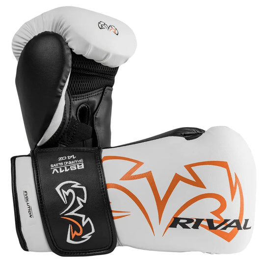 Twee Rival RS11V Evolution Bokshandschoenen Wit Oranje naast elkaar, waarbij de zijkant en binnenkant zichtbaar zijn. De witte buitenzijde met oranje Rival-logo contrasteert met de zwarte binnenvoering en polssluiting met Evolution-label. Het Wrist Lock 2-systeem zorgt voor extra stabiliteit, comfort en veiligheid tijdens intensieve bokssessies.