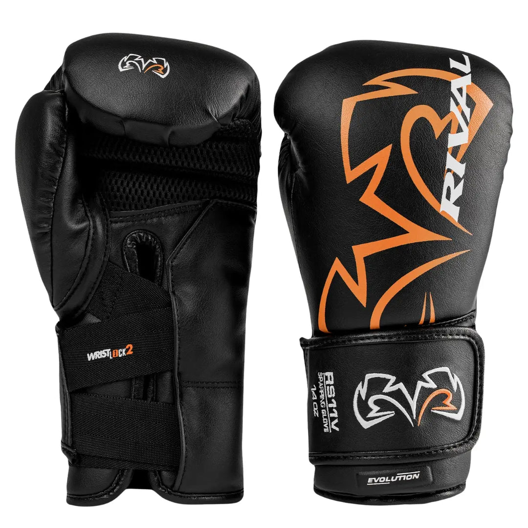 Een paar Rival Bokshandschoenen RS11V Evolution Zwart met oranje logo’s en zwarte afwerking. De ene handschoen toont het grote Rival-logo op de buitenzijde, terwijl de andere de binnenzijde met het Wrist Lock 2-sluitsysteem laat zien. De handschoenen hebben een robuuste, professionele uitstraling met optimale polsondersteuning voor sparring en training.
