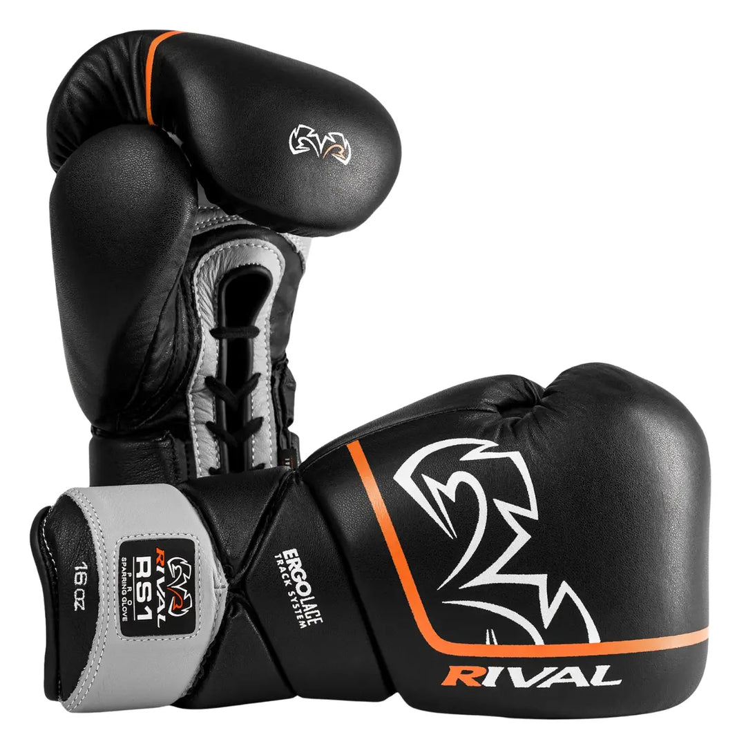 De Rival RS1 Sparring Bokshandschoenen Zwart Oranje met veter- en polssteun voor professionele boksers. Het Ergo Lace Track System zorgt voor een nauwsluitende pasvorm en uitstekende stabiliteit. De zwarte handschoenen met oranje en witte details combineren stijl, bescherming en duurzaamheid voor intensieve sparringssessies.