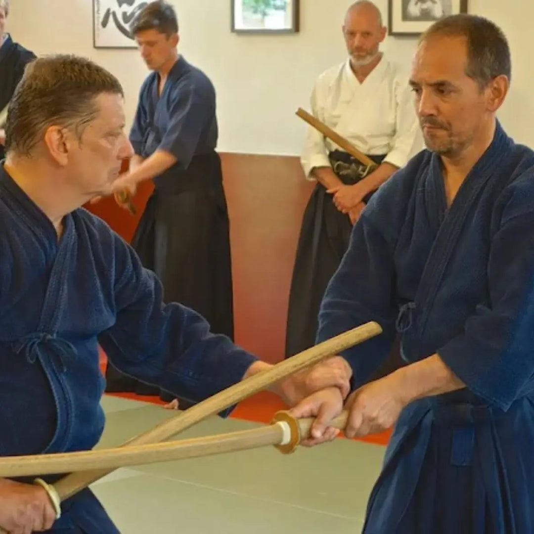 Twee mannen trainen met houten zwaarden tijdens een traditionele krijgskunstles