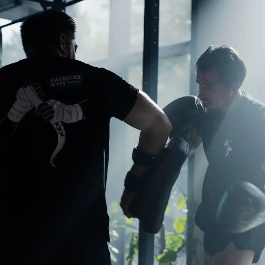 Man slaat op de pads van zijn coach tijdens vechtsporttraining