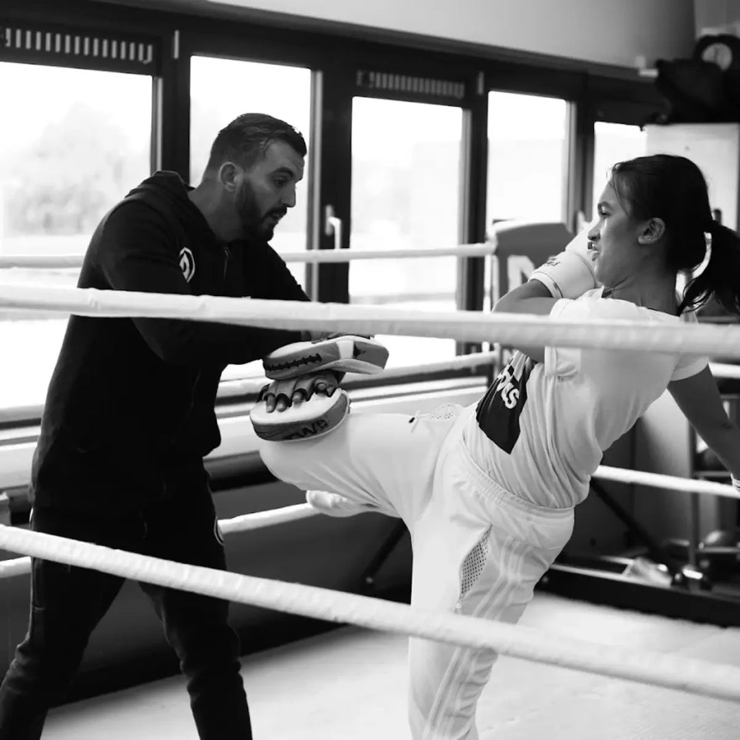 Kickbokser geeft een knie op de pads van de coach tijdens training