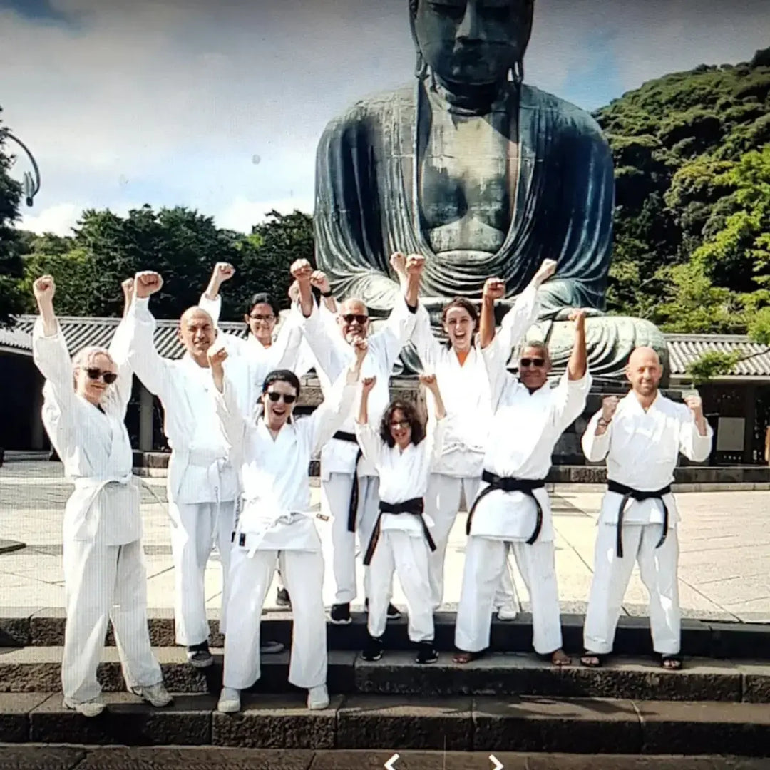 Groep kungfu-beoefenaars poseert voor een Boeddhabeeld in de trainingsruimte