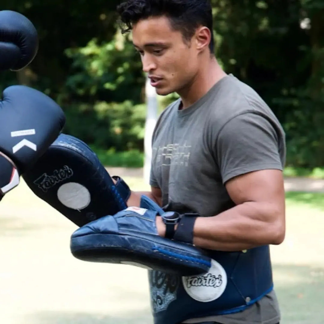 Trainer houdt pads vast tijdens vechtsporttraining