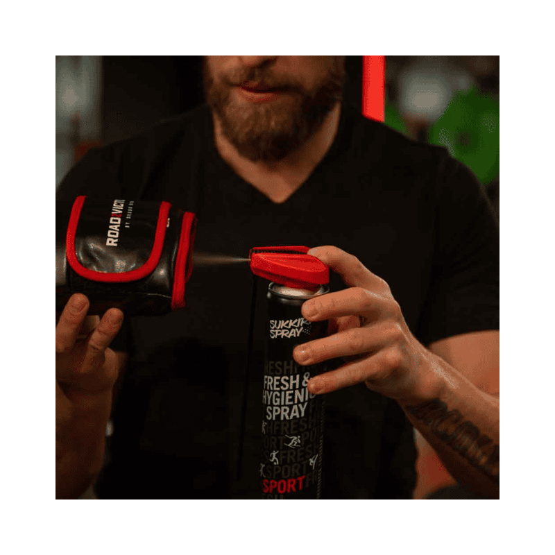 Een man gebruikt Sukkiri Spray op een bokshandschoen om het product te ontsmetten en fris te houden. De spray wordt rechtstreeks op de handschoen aangebracht