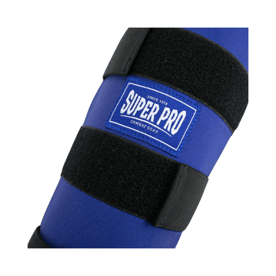 Close-up van het Super Pro logo op de blauwe scheenbeschermer, bevestigd op de voorkant van de beschermer met klittenbandsluitingen voor extra stabiliteit.