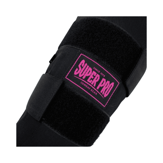 Close-up van het roze Super Pro logo op een zwarte scheenbeschermer, met zwarte klittenbandsluitingen voor een stevige pasvorm.