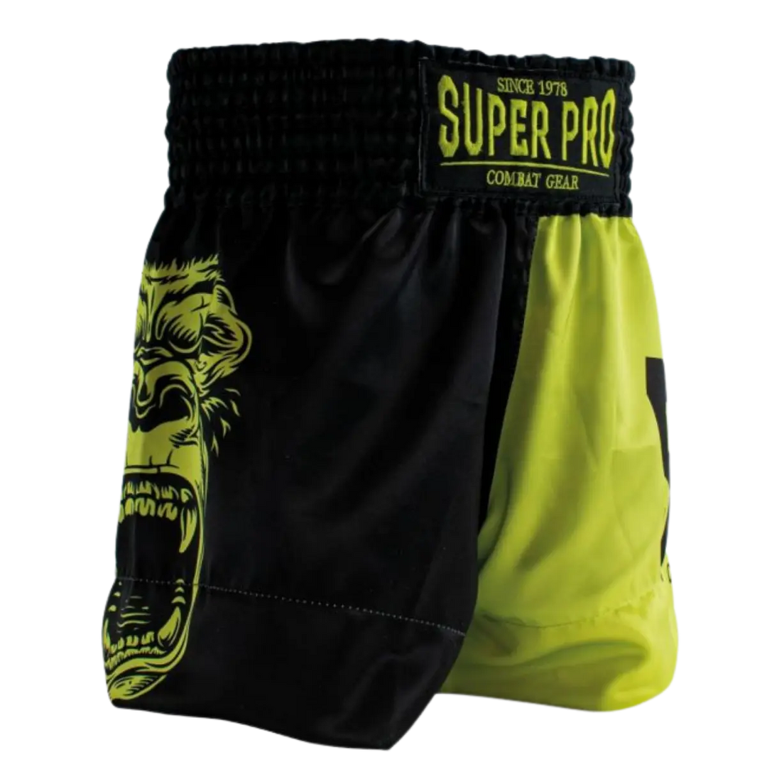 Driekwartaanzicht van het Super Pro kickboksbroekje in neon geel en zwart met opvallend gorilla-design op de zijkant. De combinatie van contrasterende kleurvlakken en de krachtige print geeft het broekje een stoere en energieke uitstraling. De brede elastische tailleband met Super Pro-label zorgt voor een stevige, comfortabele pasvorm tijdens intensieve trainingen. Dankzij het lichte en soepele materiaal biedt dit broekje maximale bewegingsvrijheid bij trappen, knieën en snelle combinaties in de gym.