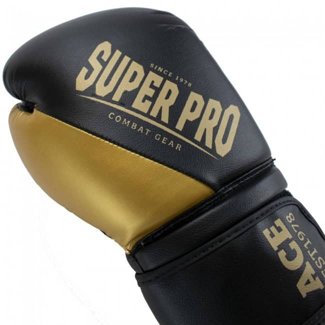 Close-up van de Super Pro Kickbokshandschoen Ace Goud, met zwart-gouden ontwerp en duidelijk zichtbaar Super Pro-logo, gemaakt voor optimale bescherming en professionele uitstraling.