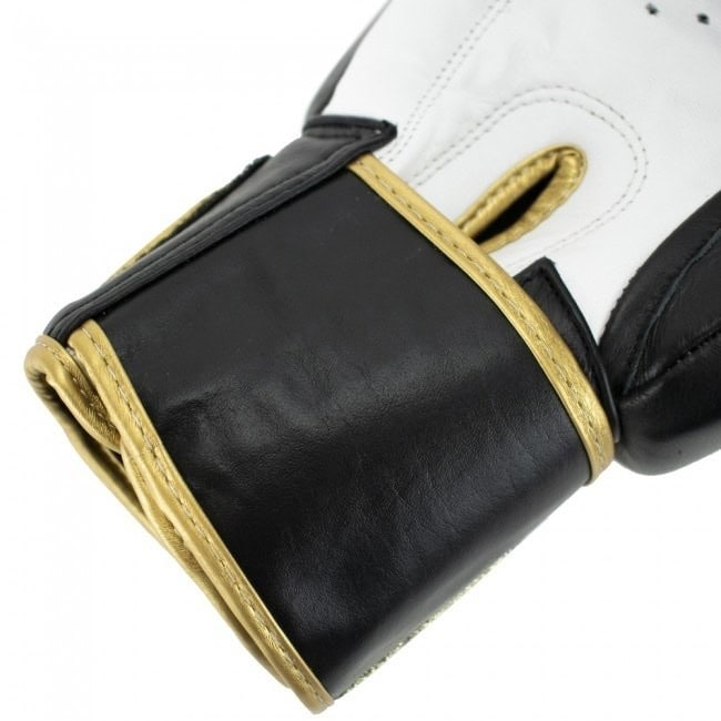 Close-up van de zwarte polssluiting van een bokshandschoen, met gouden randen en stiksel.