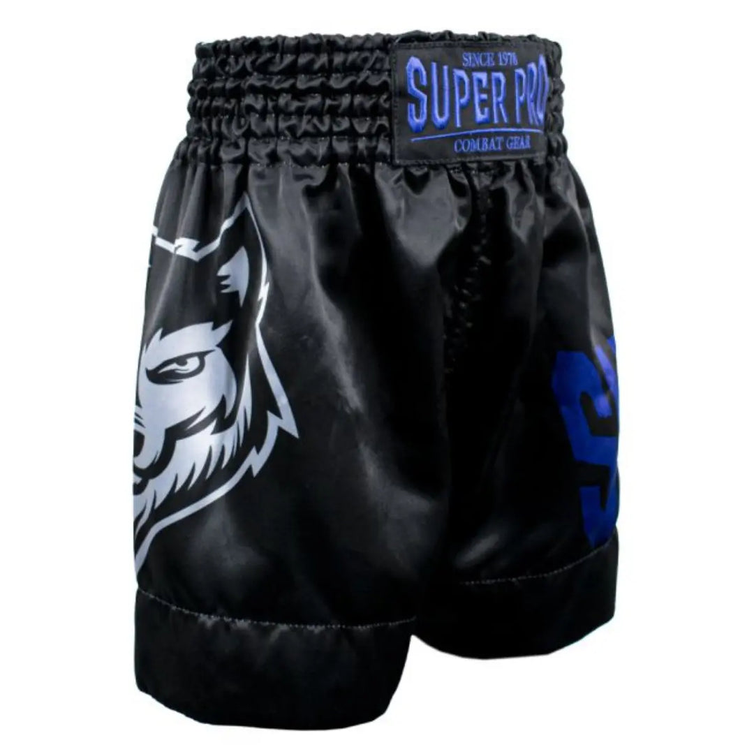 Super Pro Kickboks Broekje Kids Wolf in zwart met blauwe accenten en wolvenprint, voorzien van elastische tailleband en Super Pro logo, ontworpen voor jonge kickboksers tijdens training en wedstrijden.