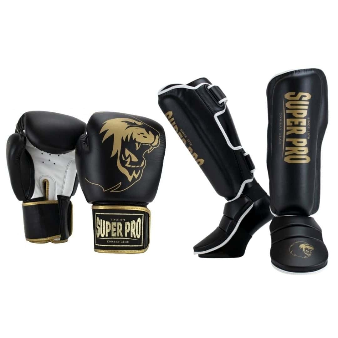 Een zwarte kickboksset met goudkleurige logo's, bestaande uit twee handschoenen met witte handpalmen en twee scheenbeschermers met witte accenten.
