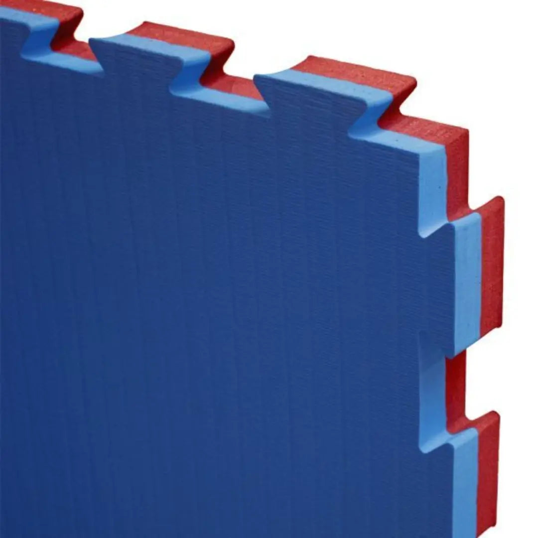 Detailfoto van een rood-blauwe puzzelmat met in elkaar grijpende randen. De Super Pro Puzzelmat Rood/Blauw is geschikt als stevige vloerbescherming voor sport- en trainingsruimtes.