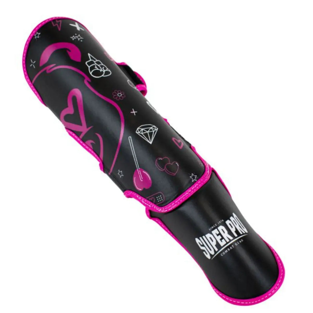 Deze afbeelding toont de scheenbeschermer schuin van bovenaf, waardoor de gehele print zichtbaar is. De combinatie van hartjes, sterren, een lolly en de cartoonbeer maakt het een vrolijk en stoer ontwerp. De Super Pro-branding staat helder op het voetpaneel.