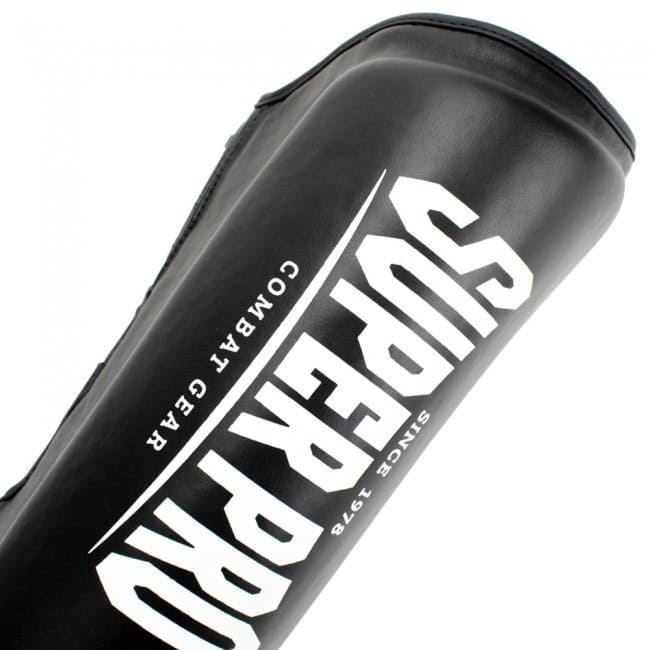 Diagonaal shot van een zwarte scheenbeschermer met een groot, wit Super Pro Combat Gear logo.