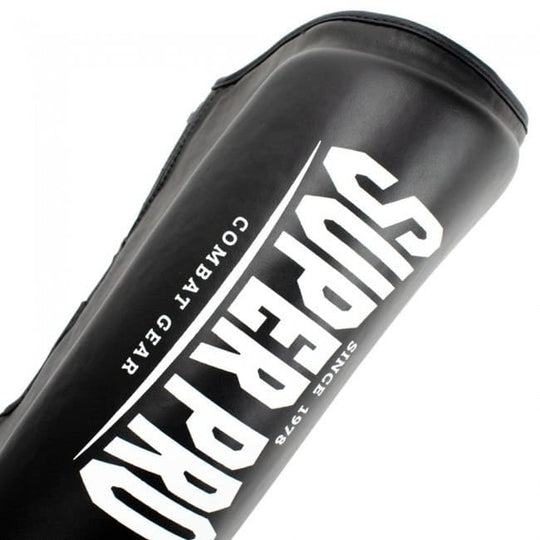 Diagonaal shot van een zwarte scheenbeschermer met een groot, wit Super Pro Combat Gear logo.