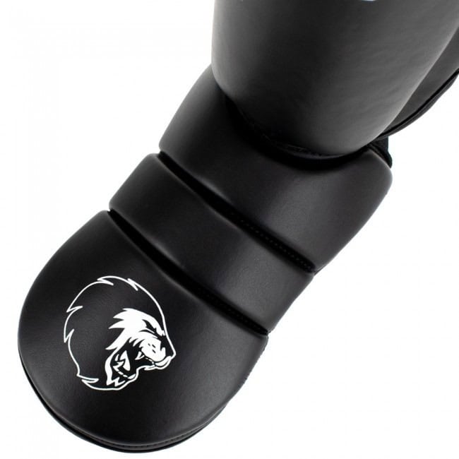 Close-up van de voetbescherming van een zwarte scheenbeschermer met een wit Super Pro leeuwenlogo.